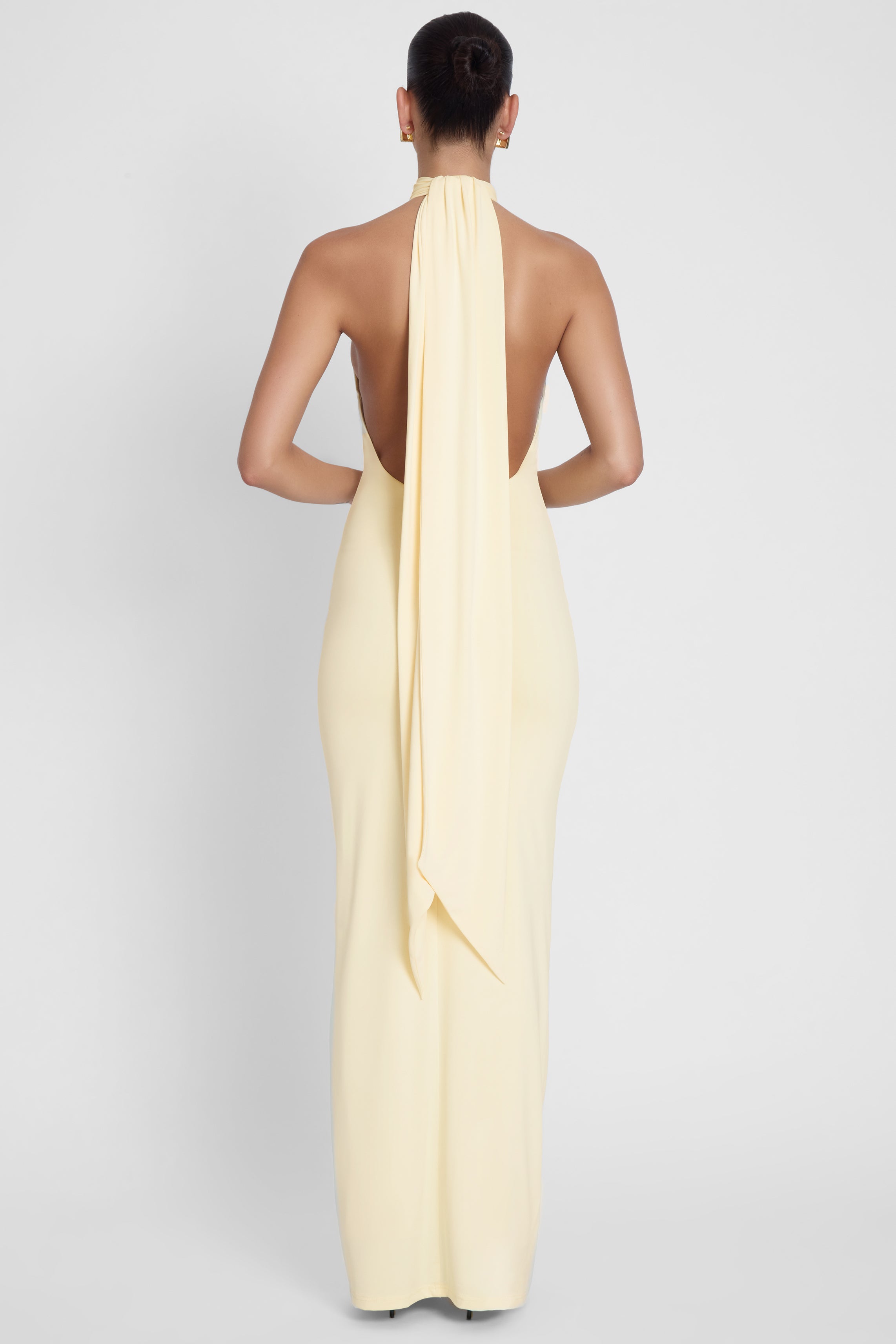 Model is wearing Alaia Drape Maxi Dress Yellow, back view.