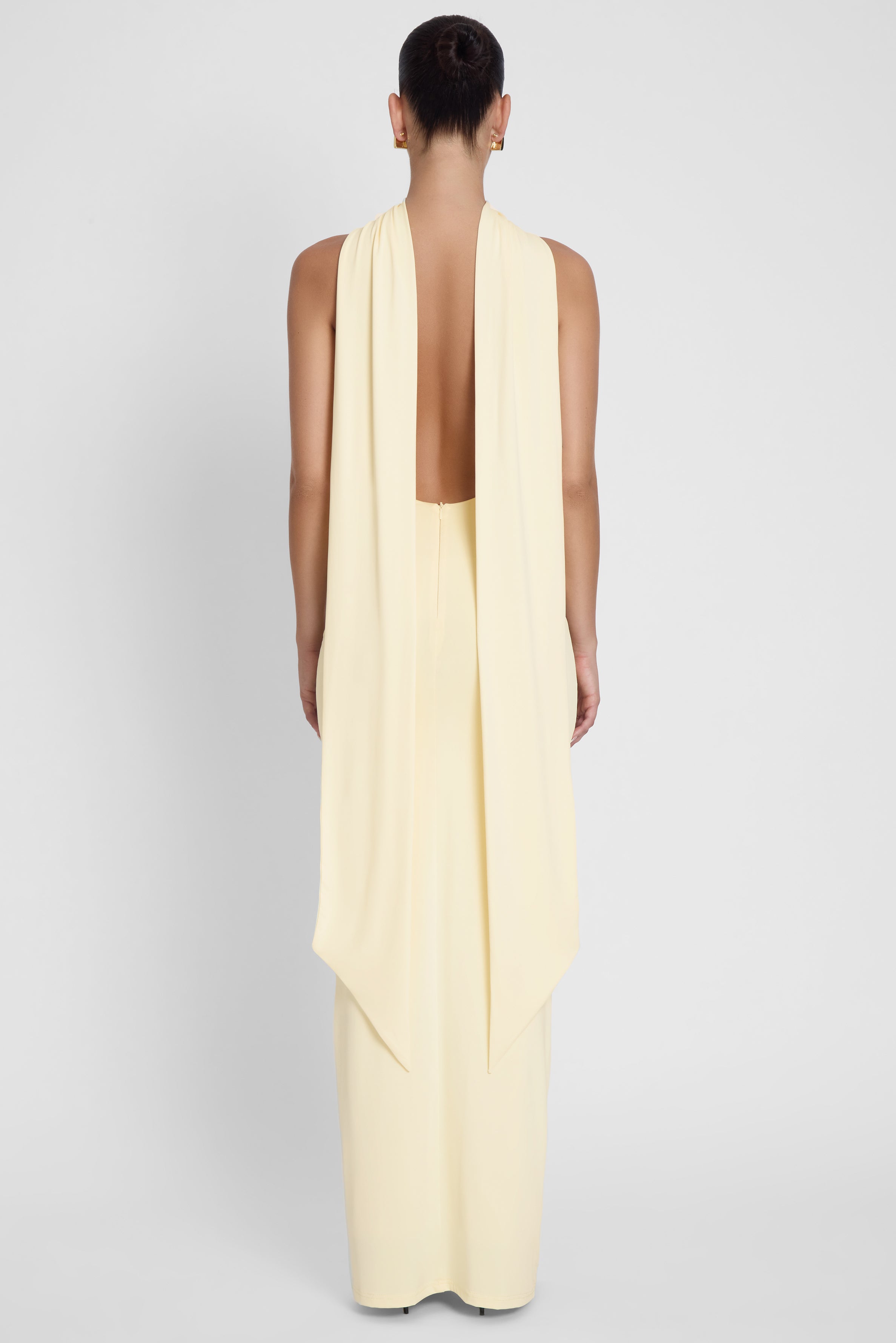 Model is wearing Alaia Drape Maxi Dress Yellow, back view.