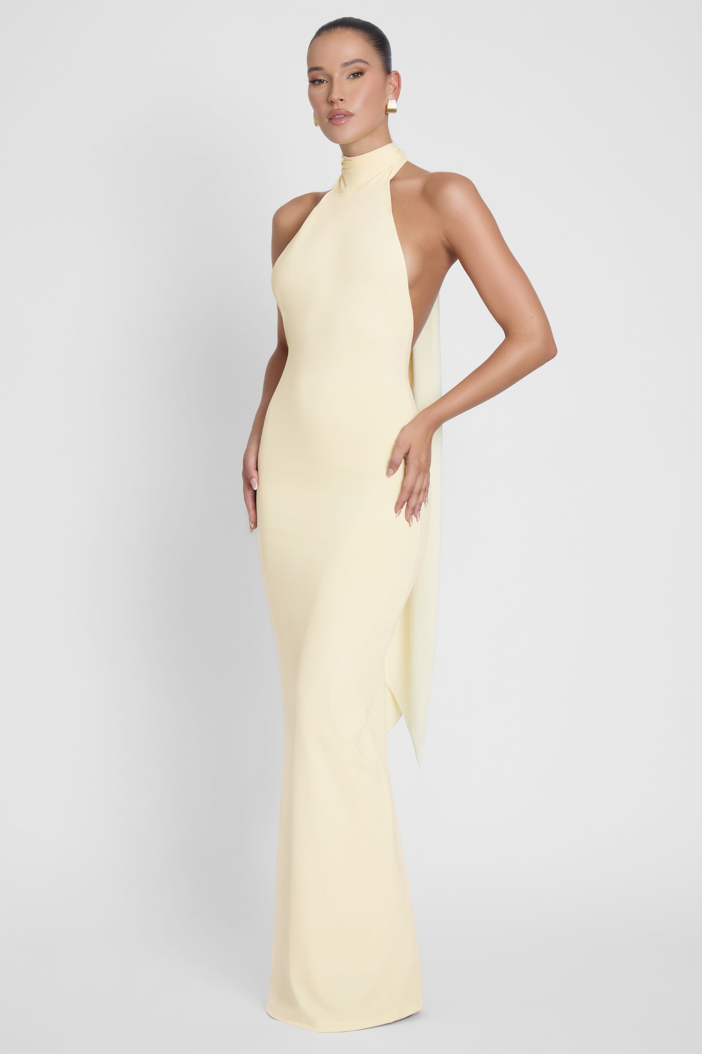 Model is wearing Alaia Drape Maxi Dress Yellow, side view.