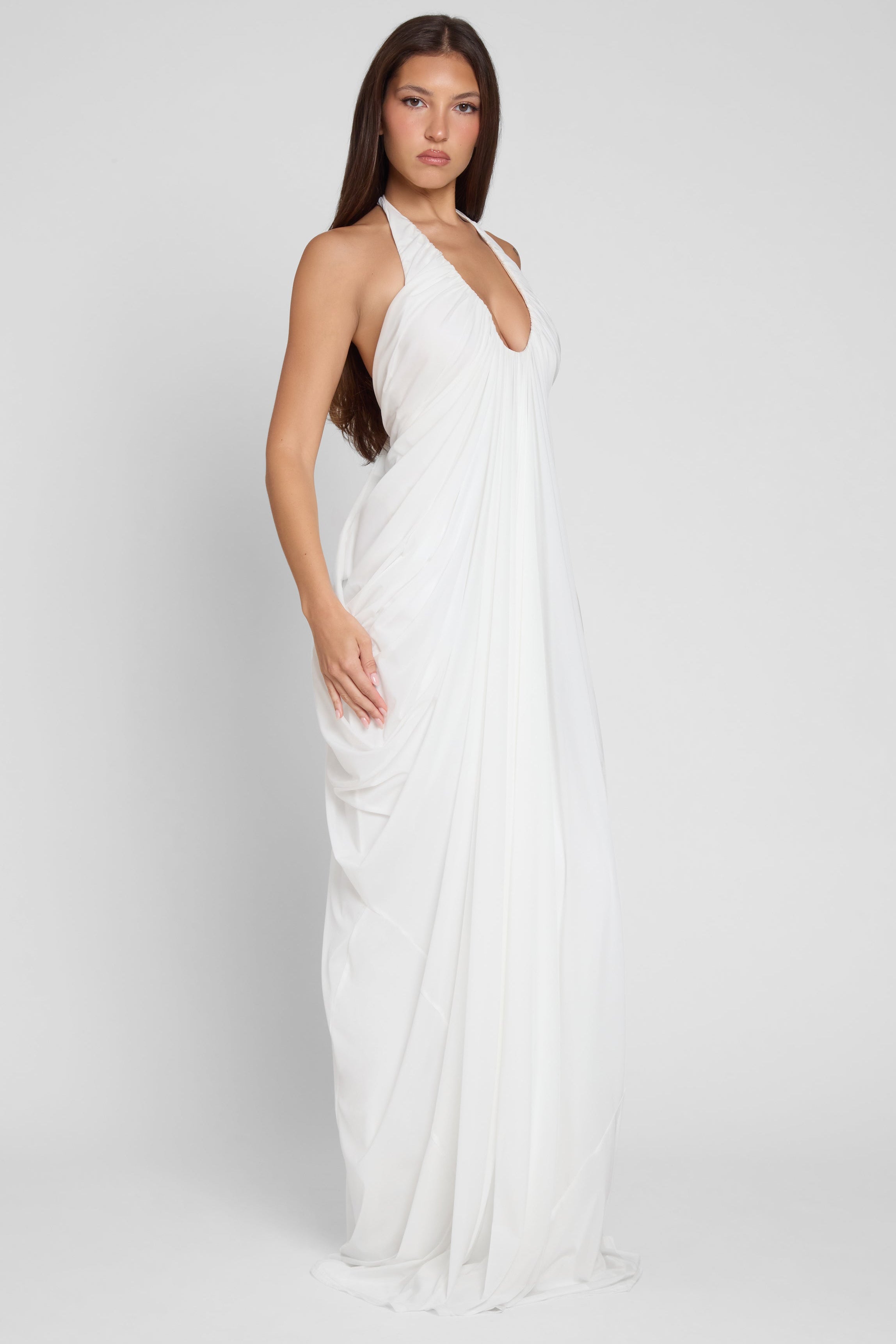 Model is wearing Cascade Drape Gown in White, side view.