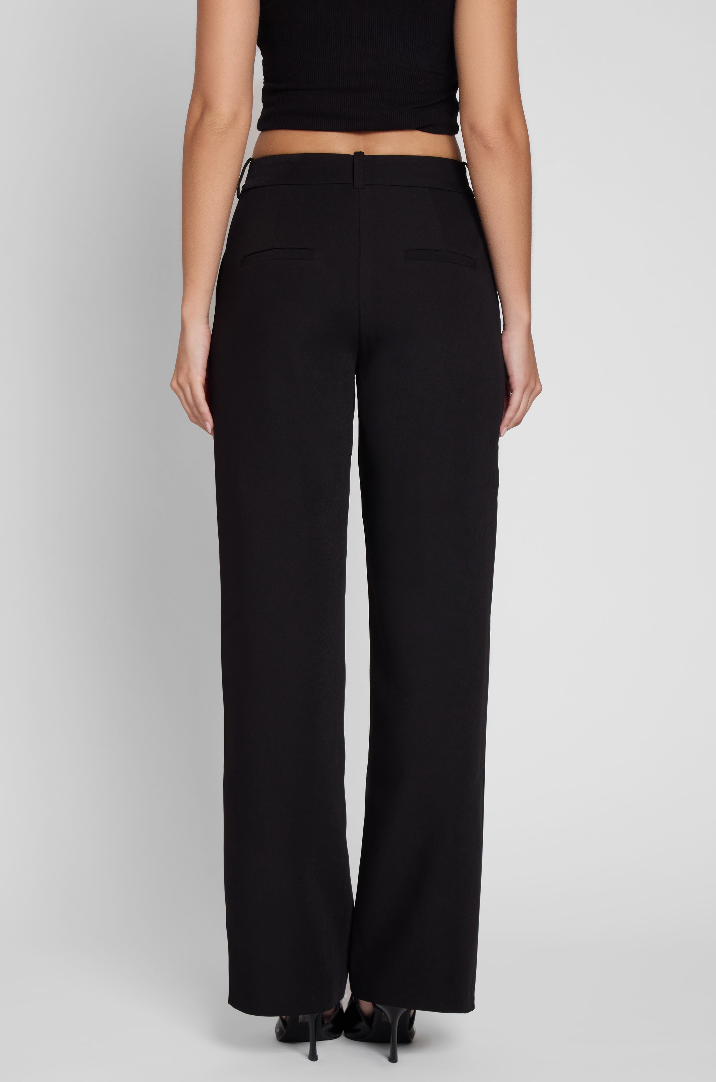 Model is wearing Classic Column Straight Trousers in Black, back view.