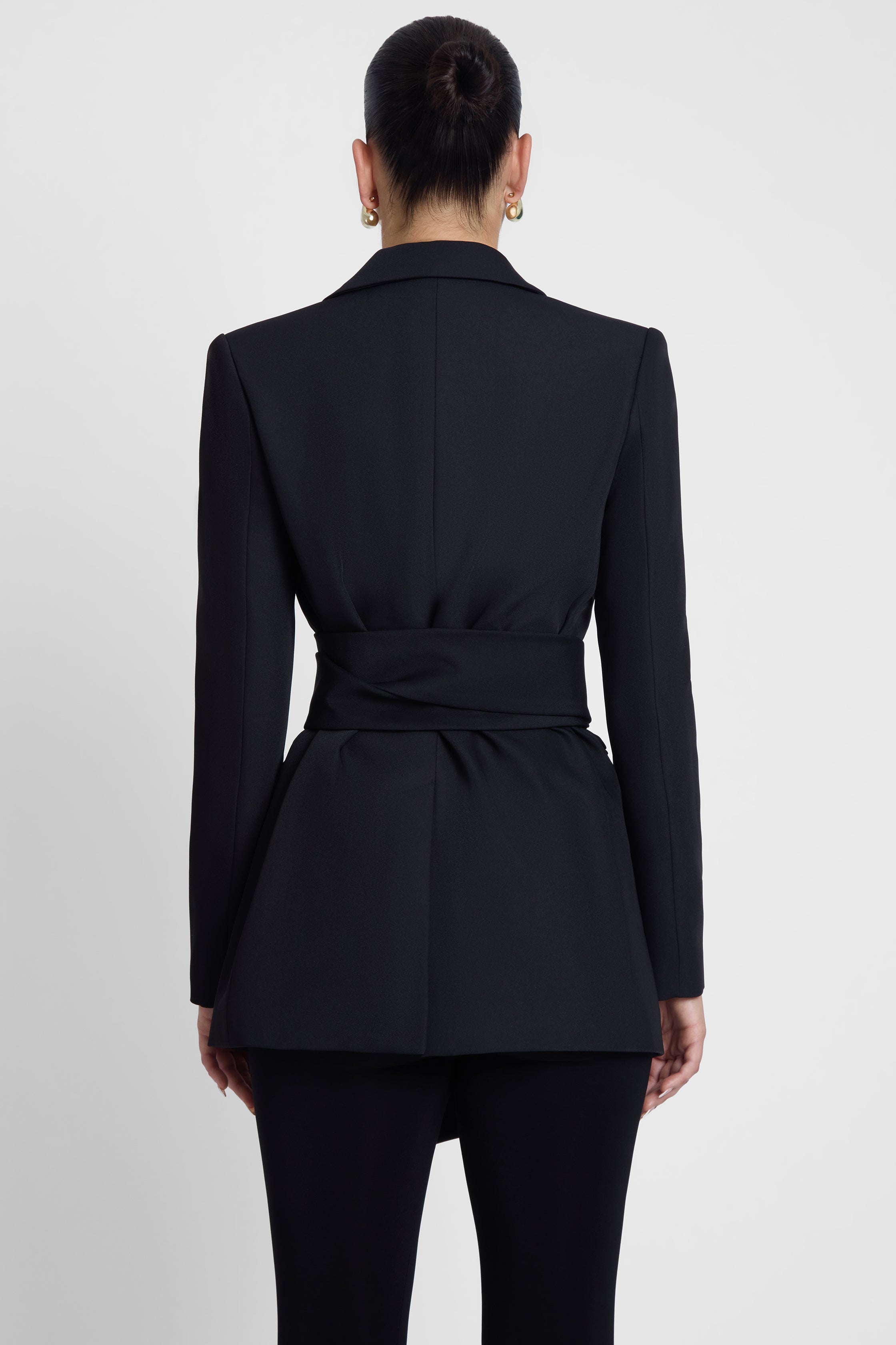 Model is wearing Classic Column Tailored Belted Blazer Black, back view.