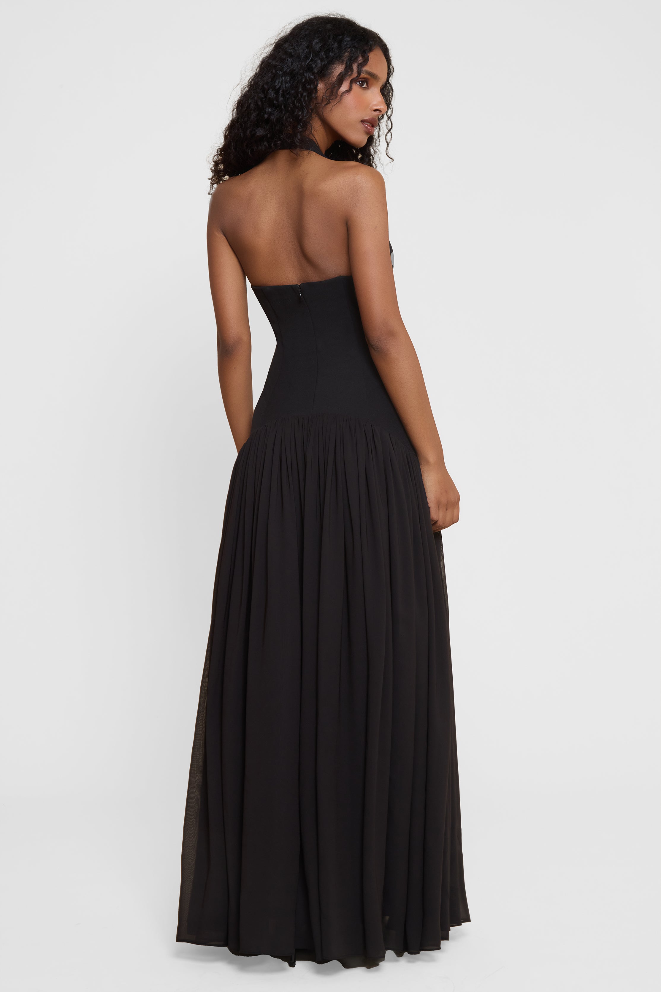 Model wearing Harmony Halter Corset Maxi Dress in Black, back view.