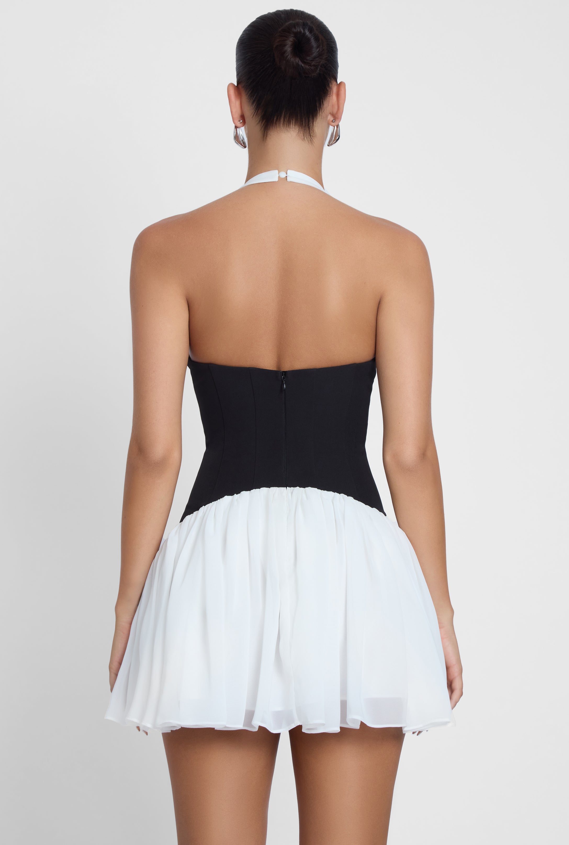 Model is wearing Harper Contrast Corset Mini Dress White, back view.