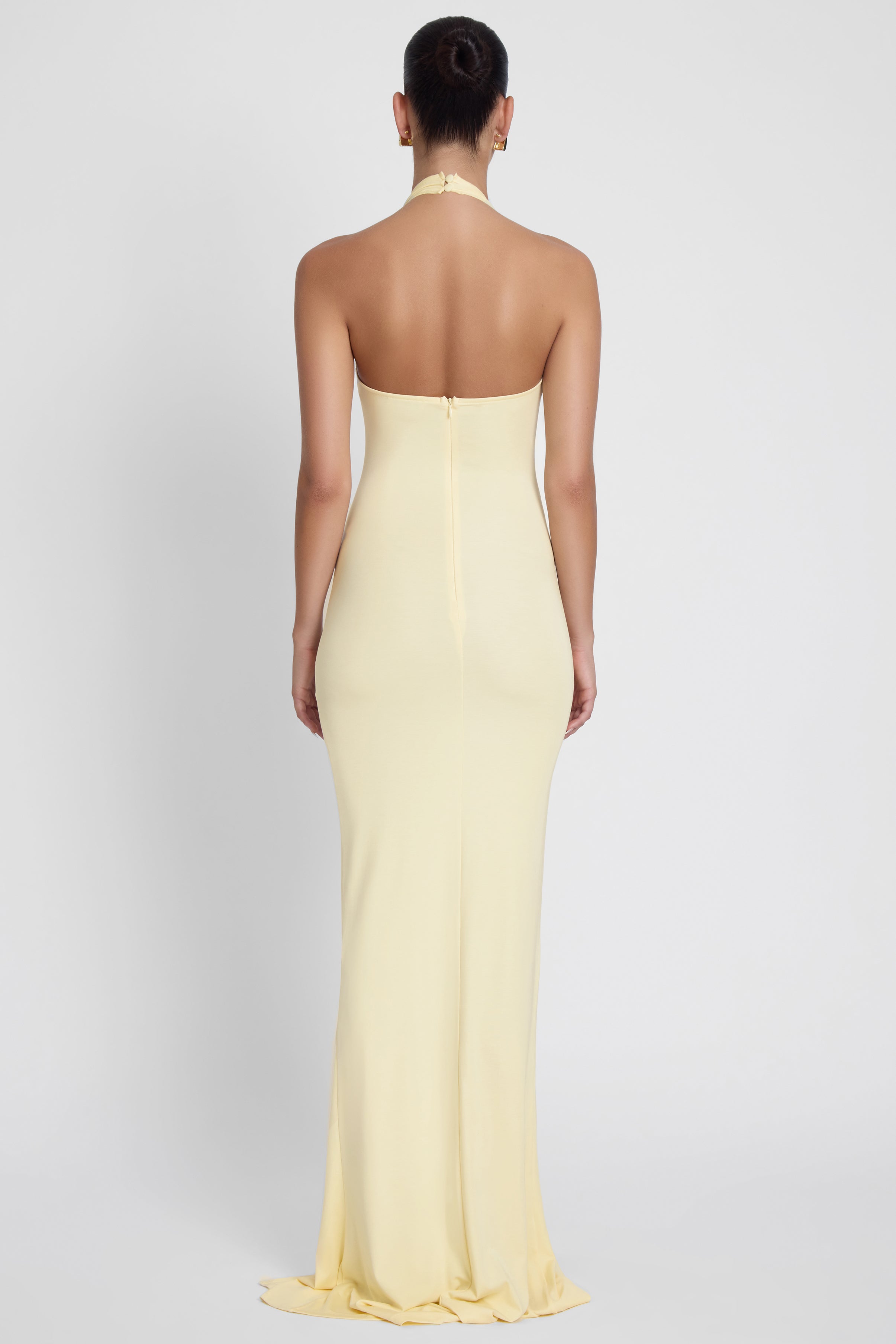 Model is wearing Heaven Halter Jersey Knot Maxi Dress Yellow, back view.