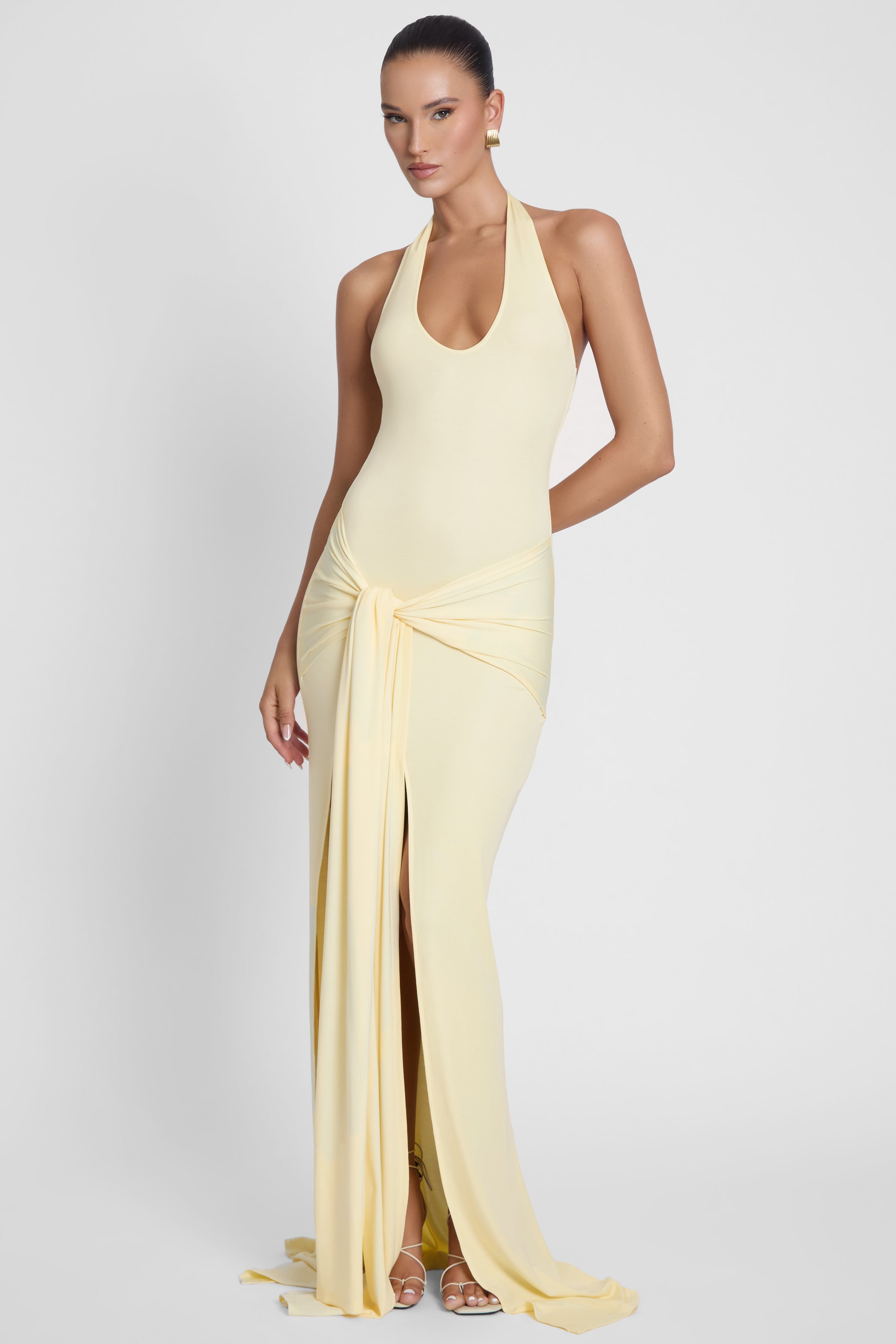 Model is wearing Heaven Halter Jersey Knot Maxi Dress Yellow, side view.