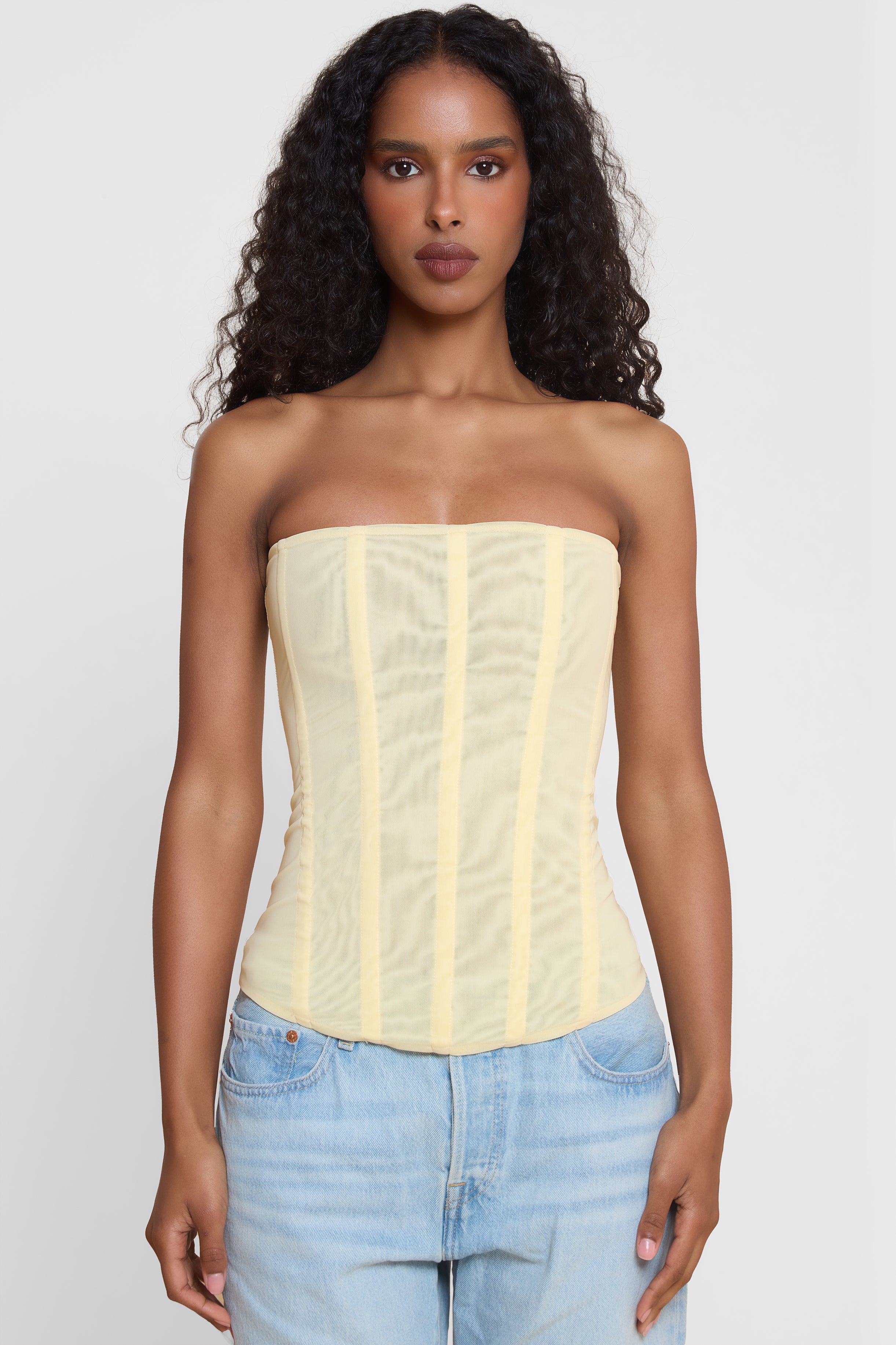 Model wearing Muse Mesh Corset Top in Yellow, front view.