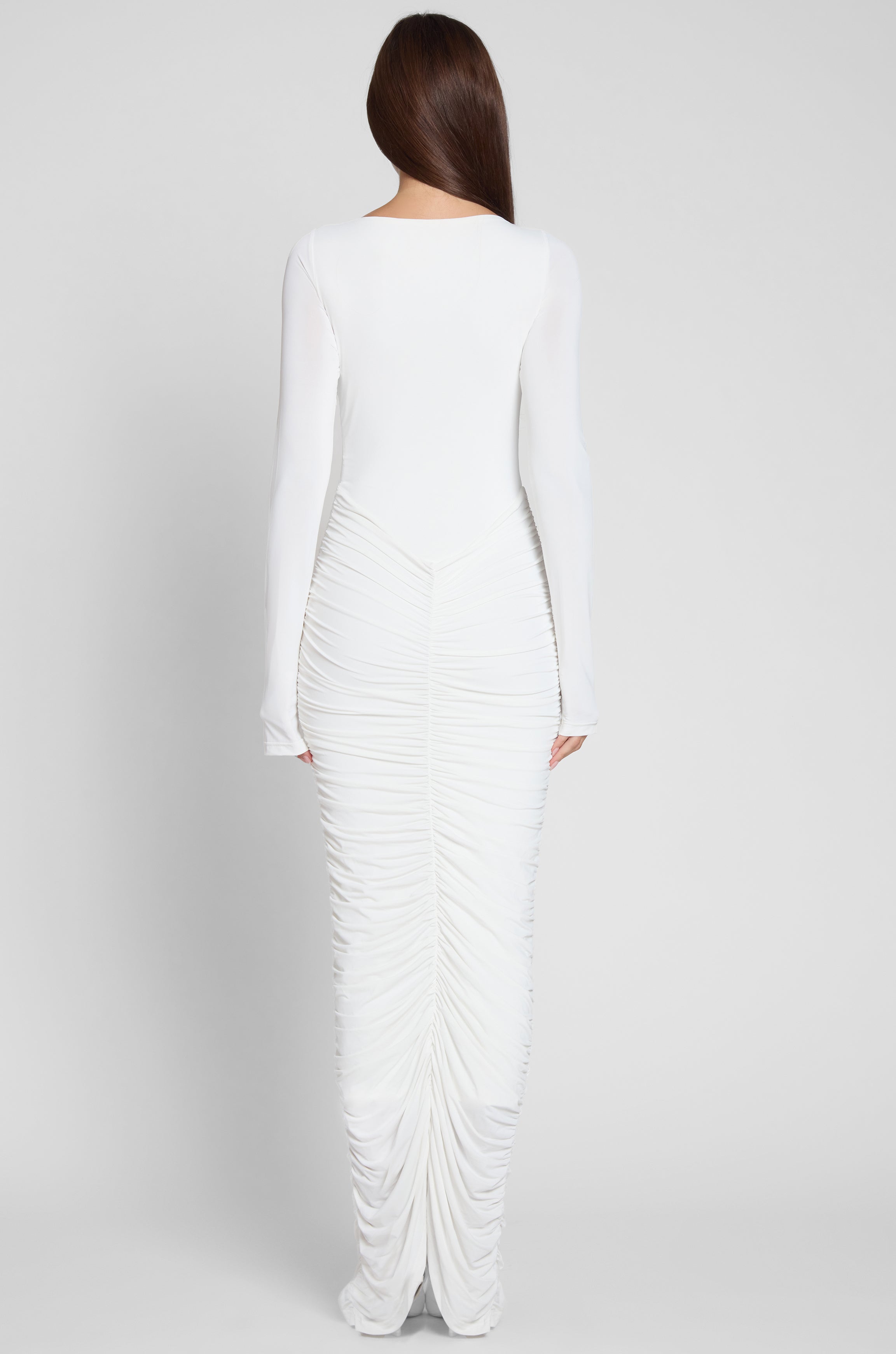 Model is wearing Rhea Ruche Maxi Dress in White, back view.