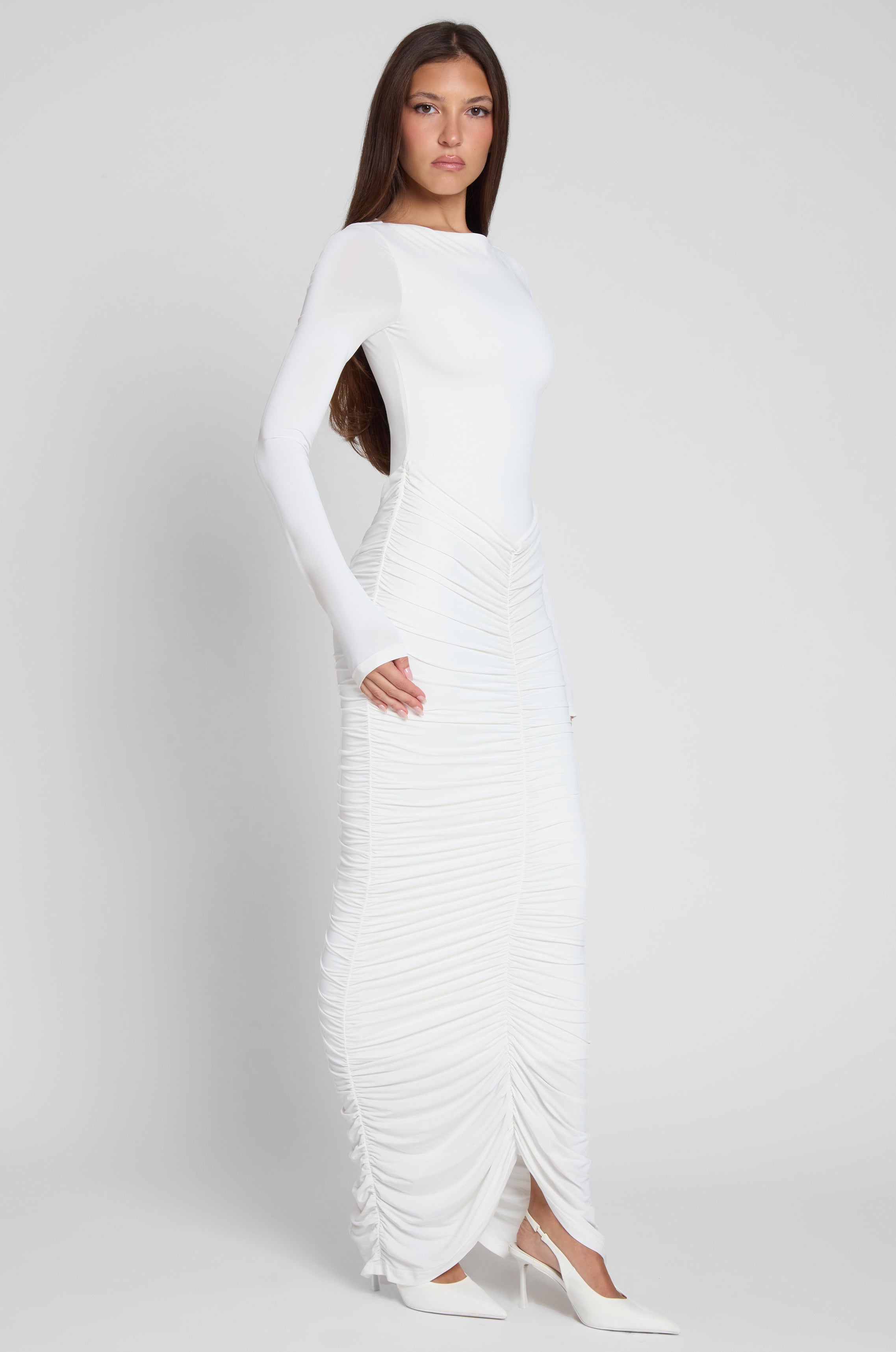 Model is wearing Rhea Ruche Maxi Dress in White, side view.