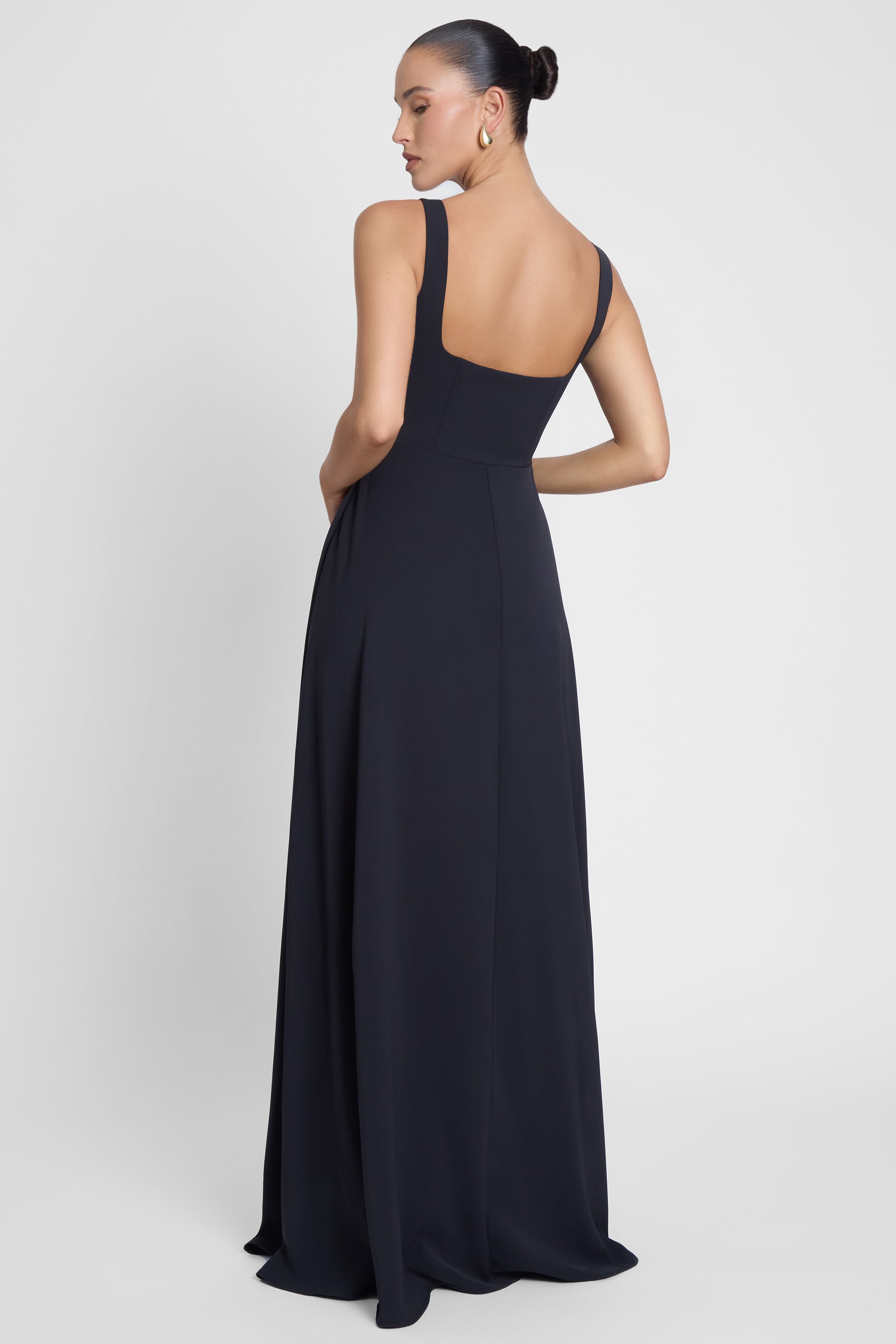 Model is wearing Siren Square Neck Corset Maxi Dress Black, back view.