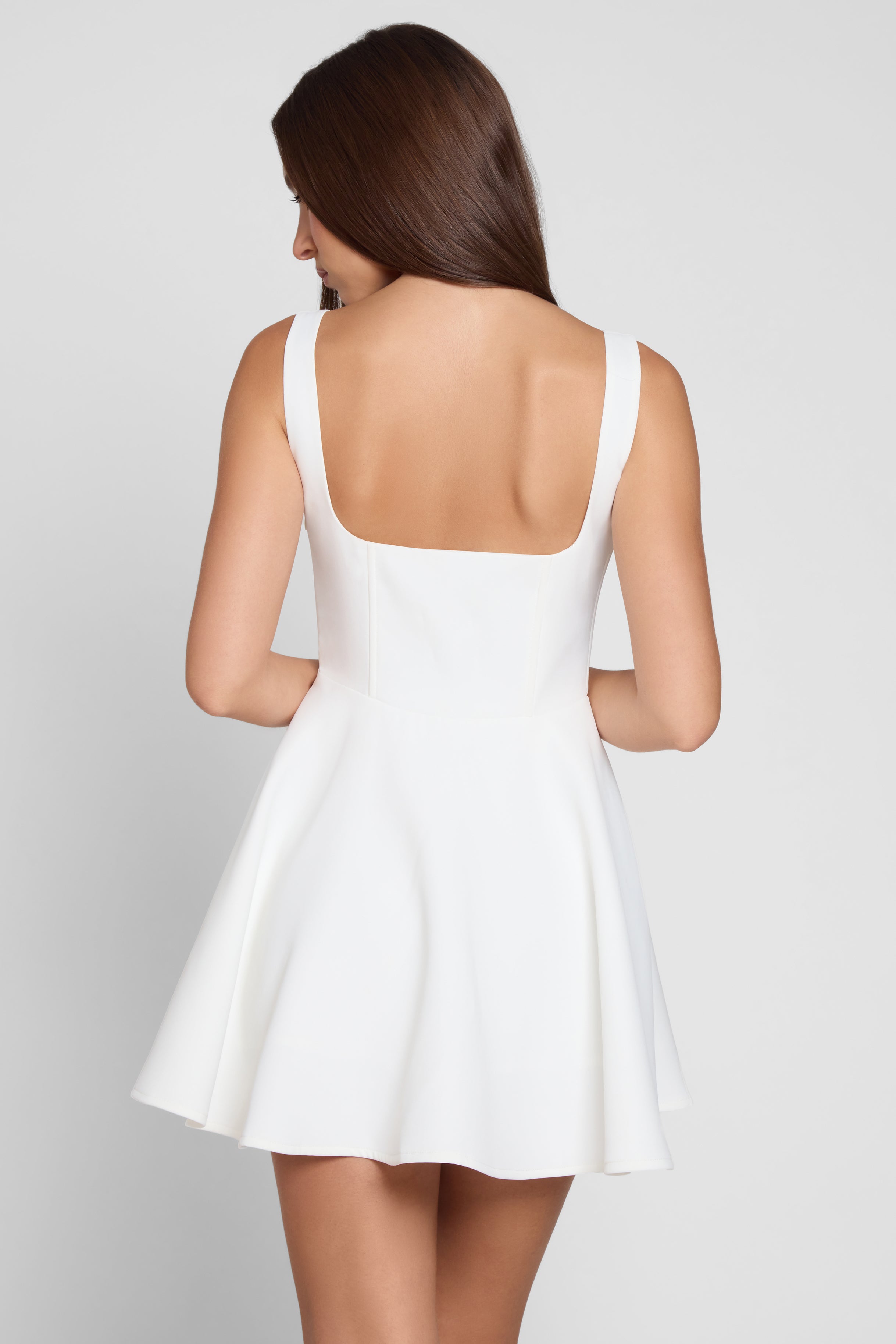 Model is wearing Sloane Square Neck Corset Mini Dress in White, back view.