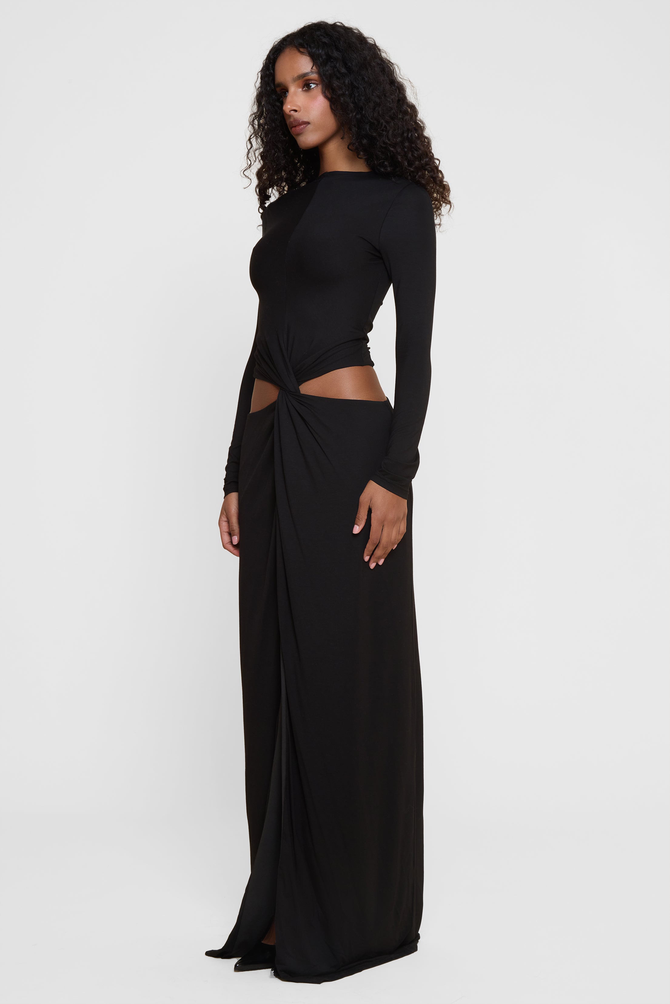 Model wearing Vacanza Drape Gown in Black, side view.